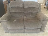 Front view of grey fabric loveseat sofa showing plush cushions and padded arm rests.