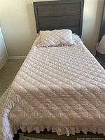 Twin size Shaker-style solid wood bed made of solid wood with an espresso color finish. Light pink quilted bedding and pillow on the bed.