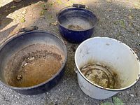 Top-down view of three enamel pails showing rust, patina, and damage.