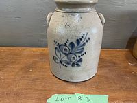 Front view of light beige crock with blue floral decoration and handles on wooden table