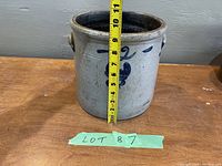 Front view of the antique stoneware crock with visible cobalt blue design and tape measure showing height approximately 10 inches.