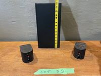 Front view of two small Bose speakers with measuring tape showing approximately 3 inches height