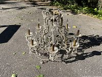 Full view of vintage crystal chandelier on ground showing all nine candle-style holders with brass bases and crystal decorations.