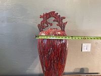 Photo showing front view of the red handmade vase with a tape measure indicating width about 11 inches.