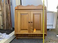 Front view of vintage hanging pine cabinet with measuring tape to show approximately 37 inches height and 30 inches width.
