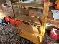 View of the full Ikea wooden shelving unit showing four shelves in a room with various items around it