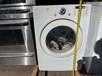 Front view of dryer with drum door closed, miscellaneous parts inside drum.