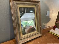 Front view of antique mirror showing the ornate wooden frame and reflective glass.
