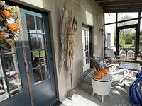 Driftwood art mounted on an exterior wall in a covered porch area with outdoor furniture and decor around.