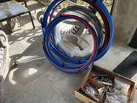View of multiple coils of PEX tubing in blue, red, and black colors, coiled and secured, arranged on patio floor near furniture.