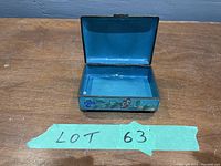 Top open view of the jewelry box showing the blue interior and floral cloisonné design on the sides.