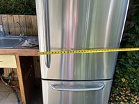 Front exterior view with stainless steel finish and tape measure showing width approx 28 inches