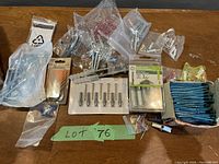 Various wall and concrete fasteners in plastic bags and packaging arranged on table.