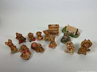 Eleven vintage Pendelfin hand painted ceramic figurines shown arranged in a row on a white background. Includes 2 miniature cottages and various anthropomorphic animals including dogs, some playing musical instruments or holding shoes.