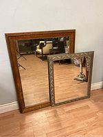 Both mirrors leaning against wall showing frames and reflective surfaces.