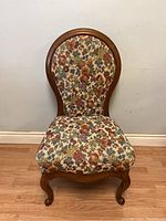 Front view of antique restored parlour chair showing floral tapestry upholstery and curved wooden frame with carved legs.