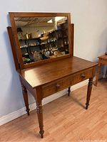 Front view of wooden vanity table with mirror and drawers showing the overall condition and details.