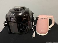 Ninja Foodi cooker and Joyoung pink electric kettle side by side showing overall condition.