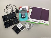 Overview of items including two iPods, Logitech mouse, charger docks, iPad covers, and battery.