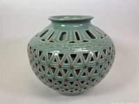 Front view of celadon vase showing open lattice design and reddish dots.