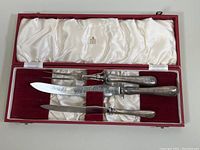 Full set of three pieces: two carving knives and one carving fork in a red velvet and white satin lined case with FIRTH logo on inside lid.