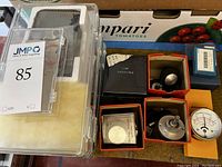 Photo showing various small machine parts, Yamaha PC-2 dial gauge, and assorted boxed components including a meter with a needle display.