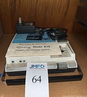 Front view of Craig Model 212 tape recorder including power adapter and owner's manual on top