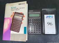 Owner's manual, HP 32SII scientific calculator, and black protective case with JMPO 96 booklet placed beside it.
