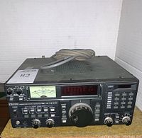 Front view of Icom IC-R7000 receiver with attached power cable showing control knobs, digital display, analog meter