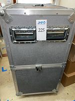 Front view of grey aluminum-reinforced hard-sided case with recessed handles and latches