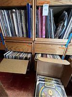Two wooden crates filled with vinyl records and a cardboard box of "Thirteen Is A Magical Number" albums