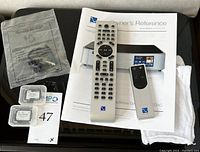 Accessories laid out on top of DAC chassis including power cord in sealed bag, two SD cards in cases, owner’s manual and two remotes