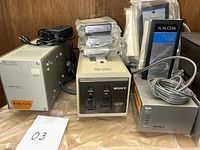 Photo showing HP DC power supply, Sony battery charger, AC adapter, and several Sony NP-1 batteries in plastic bags.