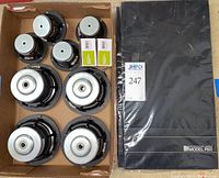 Box containing eight loose speaker drivers and two boxed tweeters alongside sealed KEF P60 grille covers