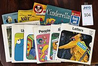 Photo showing Sesame Street 45 RPM record sets with colorful illustrated covers featuring characters such as Big Bird, Cookie Monster, and Oscar the Grouch, along with Cinderella book and record and Mary Poppins Jolly Holiday record