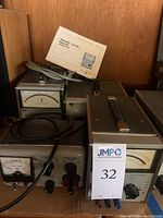 Shelf with three vintage test instruments showing front panels and cords: analog meters with needle indicators, switches, and connectors. Visible HP Power Supply 721A and sound level meter manual.