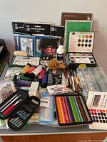 Photo showing the full assortment of art supplies including pads, acrylic paints, brushes, pencils, watercolor set and organizing trays.