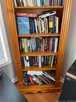 Front view showing entire pine bookcase loaded with books for scale and structure.