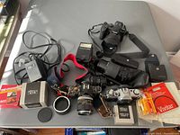 Overview of lot including Canon cameras, lenses, flash, straps, and accessories arranged on table.