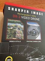 Box front showing brand, product name, and features like video & stills capability, pivoting camera lens, and 360-degree flight performance.