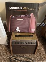 Fishman Loudbox Mini Charge amplifier and its box positioned on carpet with a power cable laying in front.