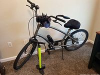 Full view of the silver men's Townie bicycle with included green bike pump standing beside it.