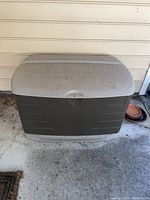 Front view of the large Rubbermaid outdoor storage container, showing dirt and wear on the lid and body.