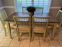 Full view of dining table with six chairs around it and faux plant centerpiece on table