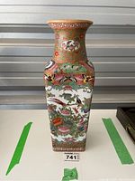 Front view showing colorful floral and bird patterns with square body and flared neck.