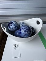 White ceramic bowl holding blue and white patterned ceramic balls, front angle