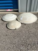 Three glass ceiling light fixtures on the floor showing various sizes and mounting clips.