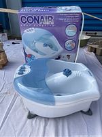 Photo of Conair foot spa unit placed outside with original box showing product image and features.