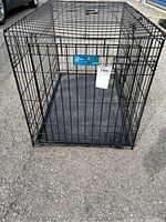 Full front view of the black metal folding crate with front door in closed position, showing the crate's structure and size.