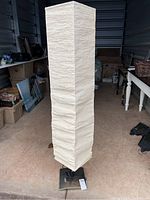 Full view of tall Ikea floor lamp with textured white fabric shade in a vertical rectangular shape and square metal base.